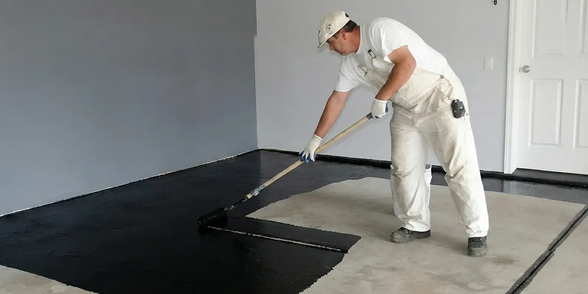 basement waterproofing professional applying waterproof coating to protect a basement floor in Cleveland, OH
