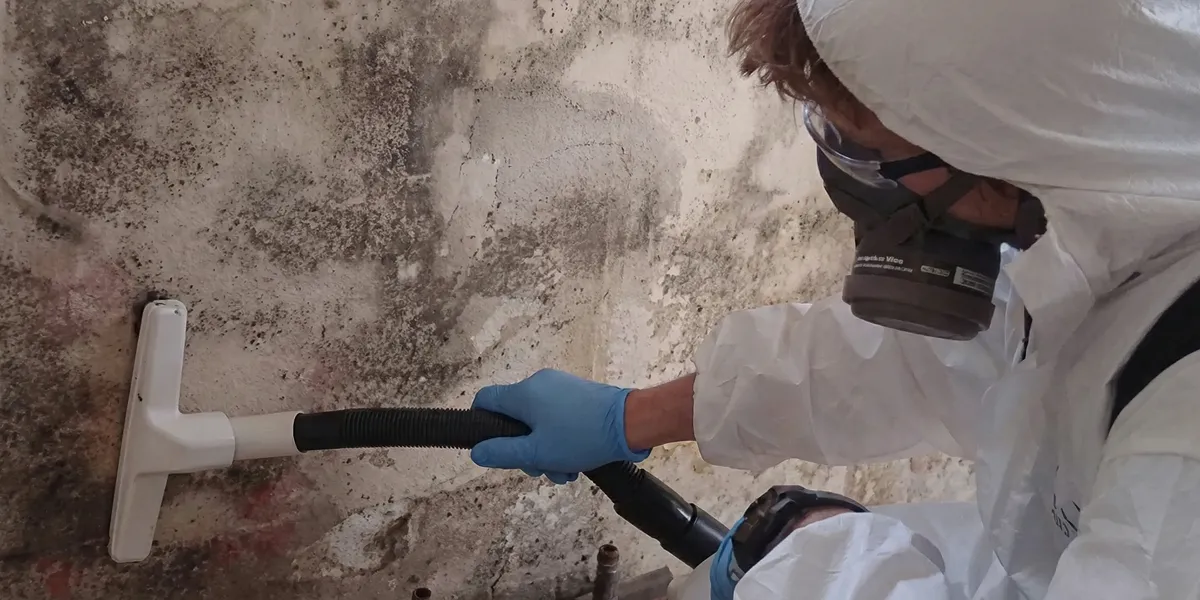professional mold removal technician wearing protective equipment removing mold from a wall in Cleveland, OH